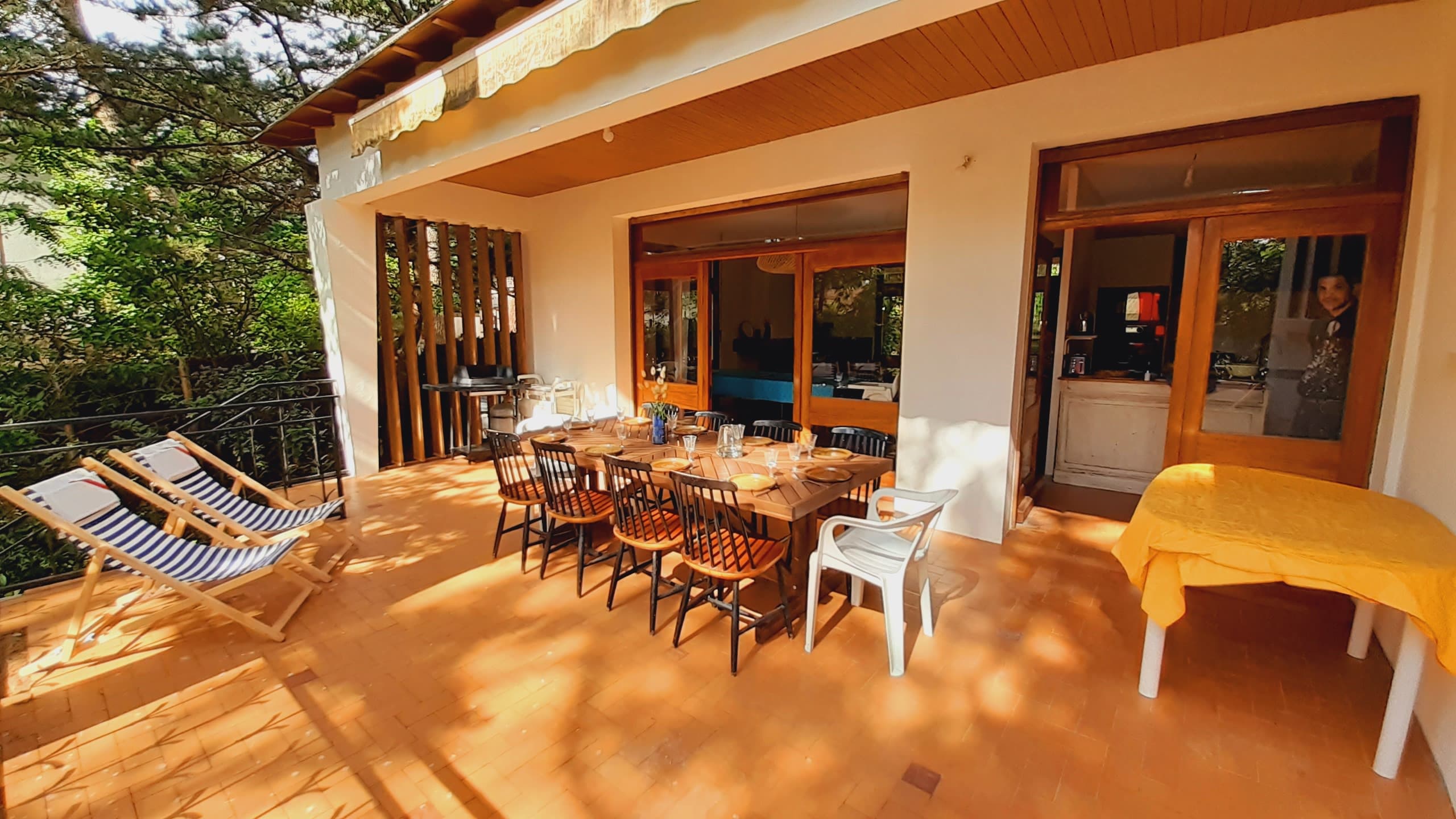 Terrasse orientée Est en surplomb du jardin, avec un store banne, du mobilier extérieur et un barbecue gaz
